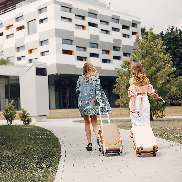Two women walking down a path with luggage, exploring options for condos for rent.