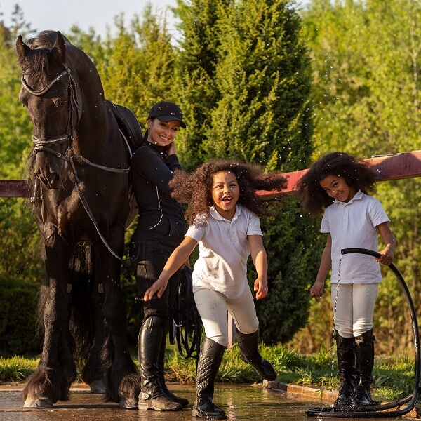 Deux filles et une femme se tiennent à côté d'un cheval dans un environnement extérieur