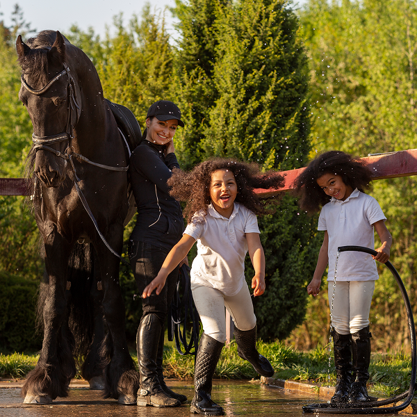 Une femme et deux enfants se tiennent à côté d'un cheval, illustrant une activité d'équitation.
